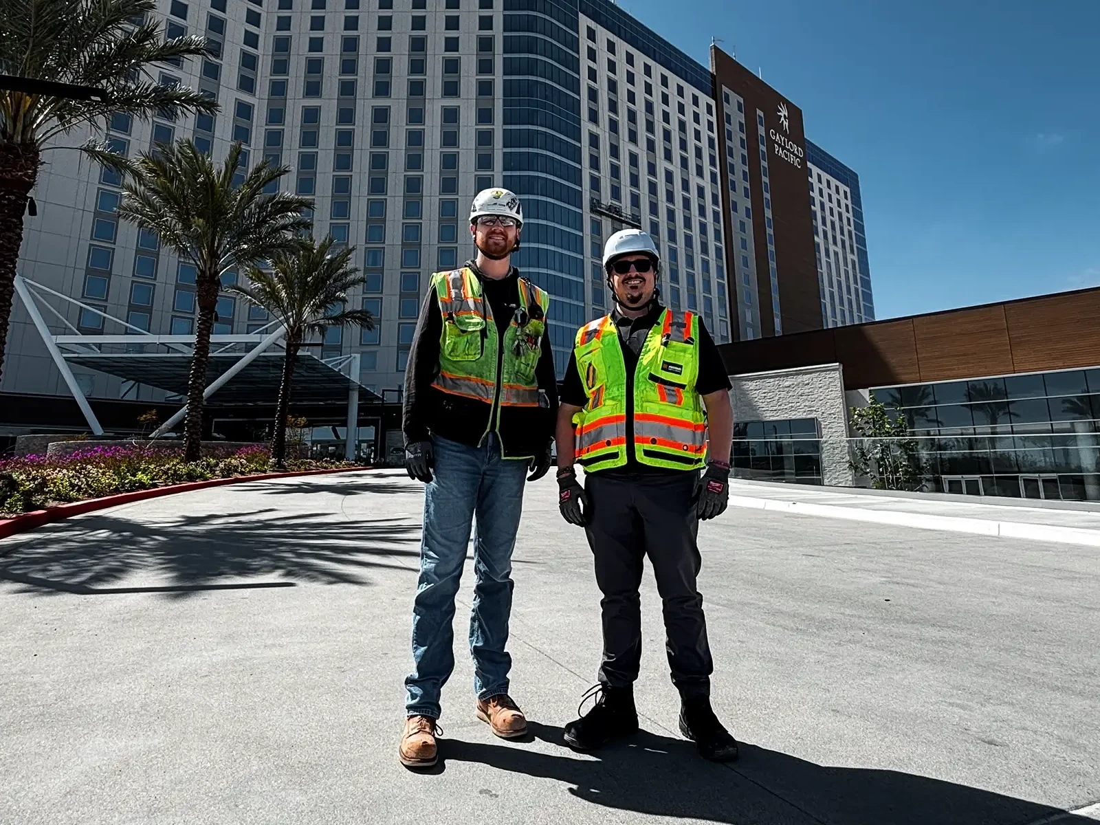 Deux membres de l'équipe de construction en tenue de sécurité se tiennent devant le Gaylord Pacific Resort, qui a été protégé par l'alarme incendie temporaire WES3.
