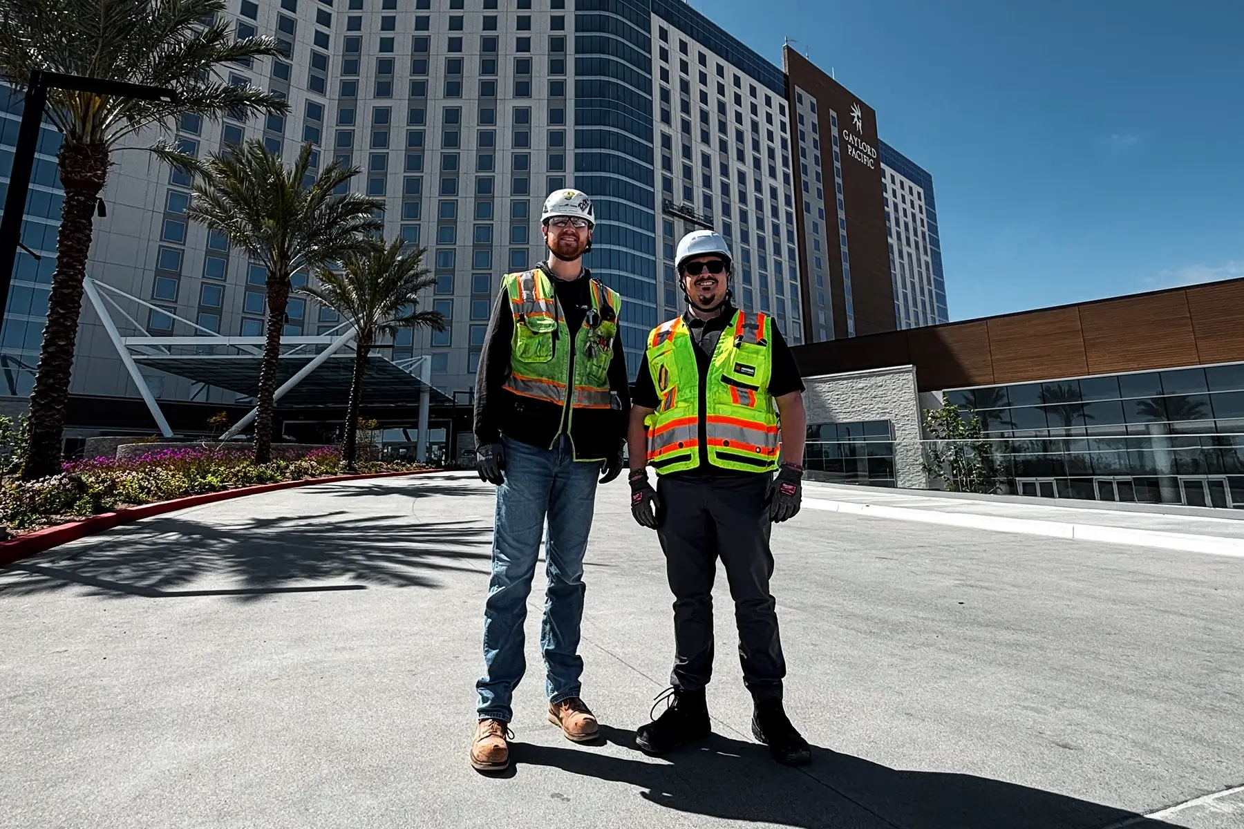 Two members of the construction team in safety gear stand in front of the Gaylord Pacific Resort, which was protected by the WES3 temporary fire alarm.