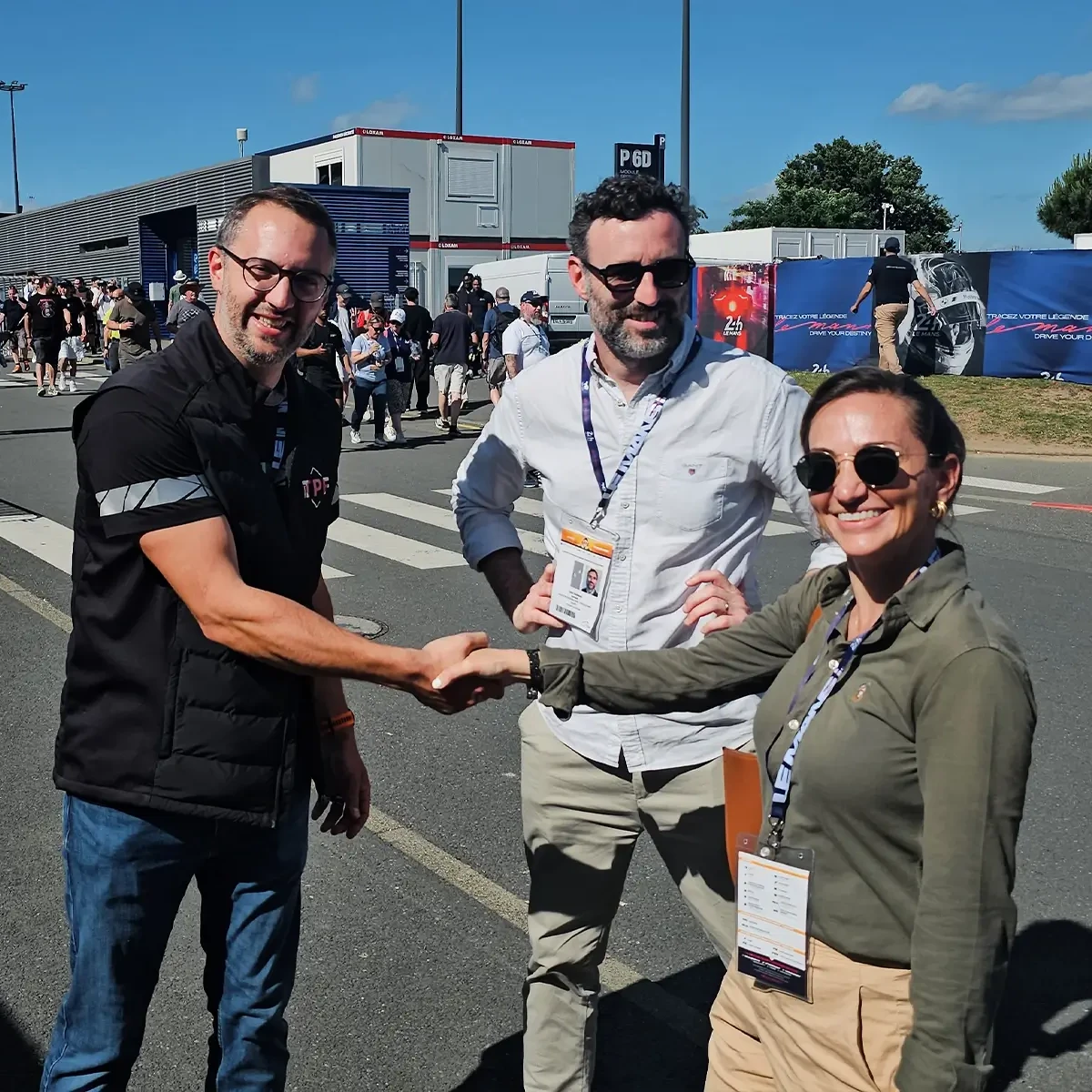 Trois membres de l'équipe de projet se serrant la main à l'extérieur des paddocks de l'équipe lors des 24 Heures du Mans