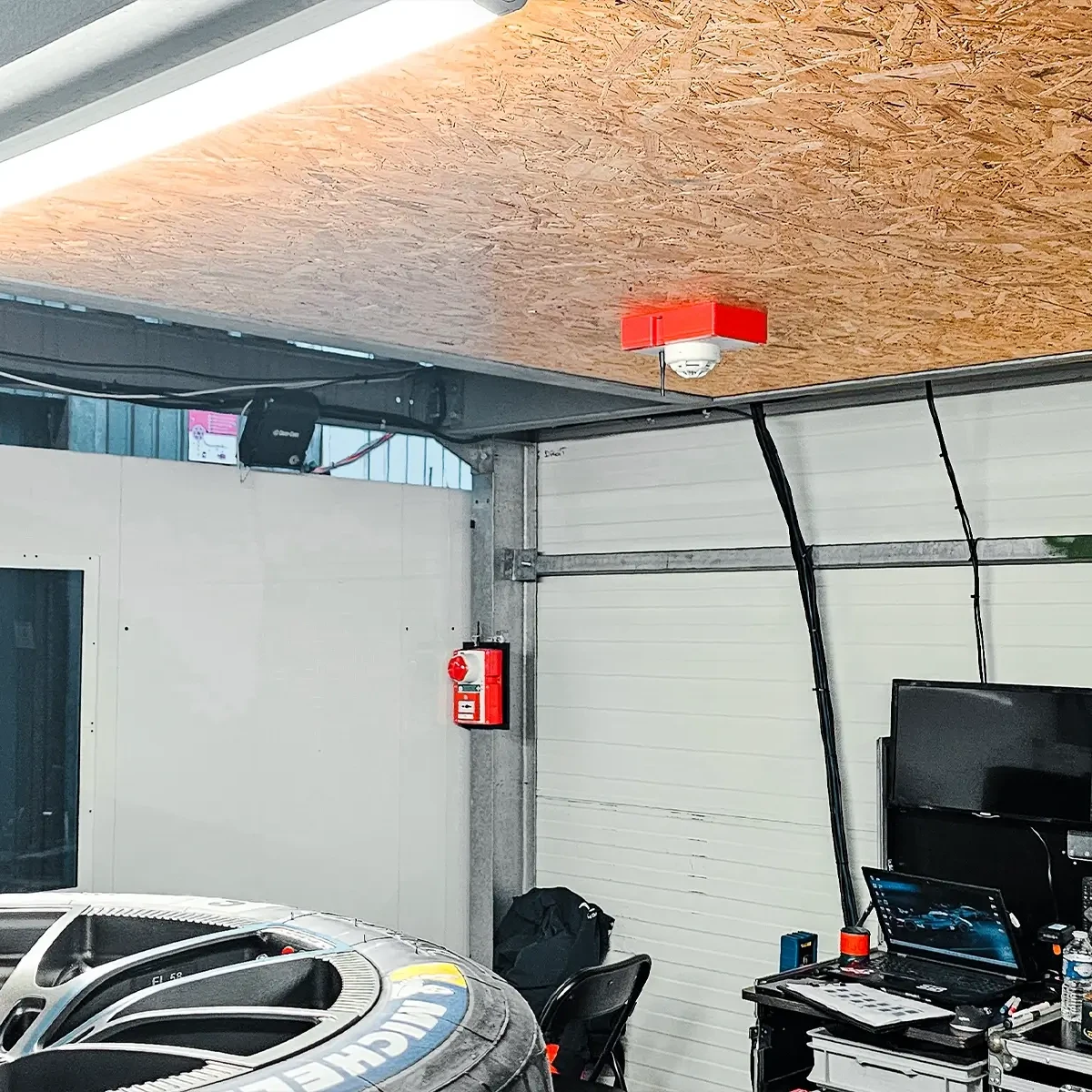 Détecteur WES3 au plafond et un déclencheur d'alarme mural dans le garage d'une équipe du Mans