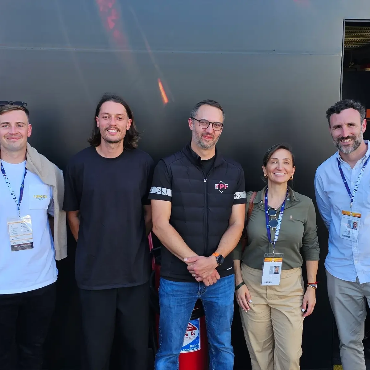 Cinq membres de l'équipe de projet se tiennent ensemble devant un bâtiment de paddock au Mans