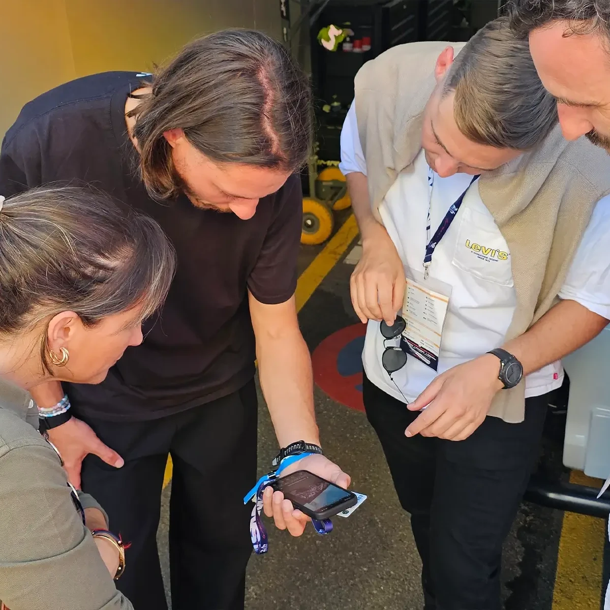 Quatre personnes regardant un téléphone mobile affichant des informations sur un système d'alarme incendie au Mans