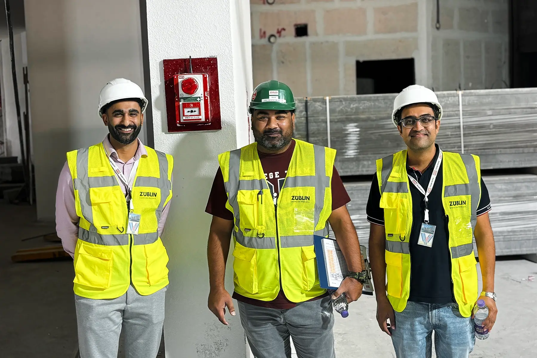 The Züblin HSE team standing next to a WES wireless fire alarm system unit.