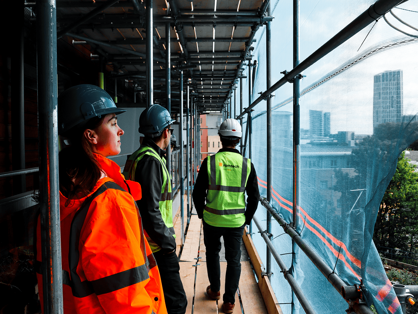 Travailleurs de la construction debout sur un échafaudage de haut niveau surplombant les gratte-ciel de la ville au loin.